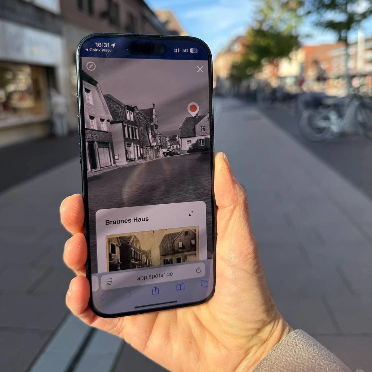 Smartphone-Ansicht der Dülmener AR-Tour: Die Marktstraße erscheint in historischer Schwarz-Weiß-Ansicht mit der Station Braunes Haus