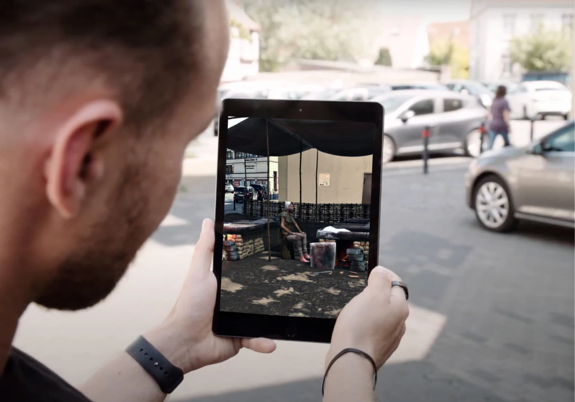 Ein Besucher blickt durch ein Tablet auf eine historische AR-Szene der Soester Stadttour mitten im heutigen Straßenbild