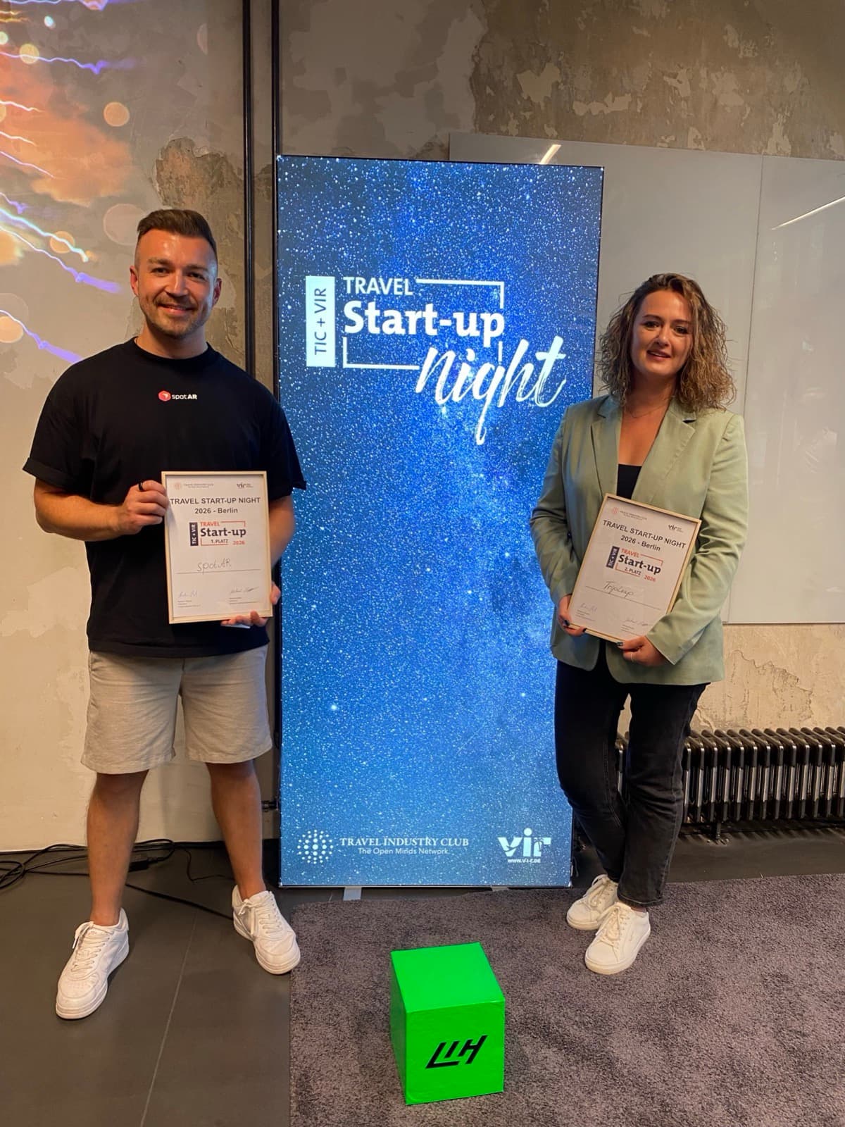 Viktor Waal von spotAR mit der Urkunde für den 1. Platz bei der TIC & VIR Travel Start-up Night 2026 in Berlin, daneben die Zweitplatzierte von TripLeap