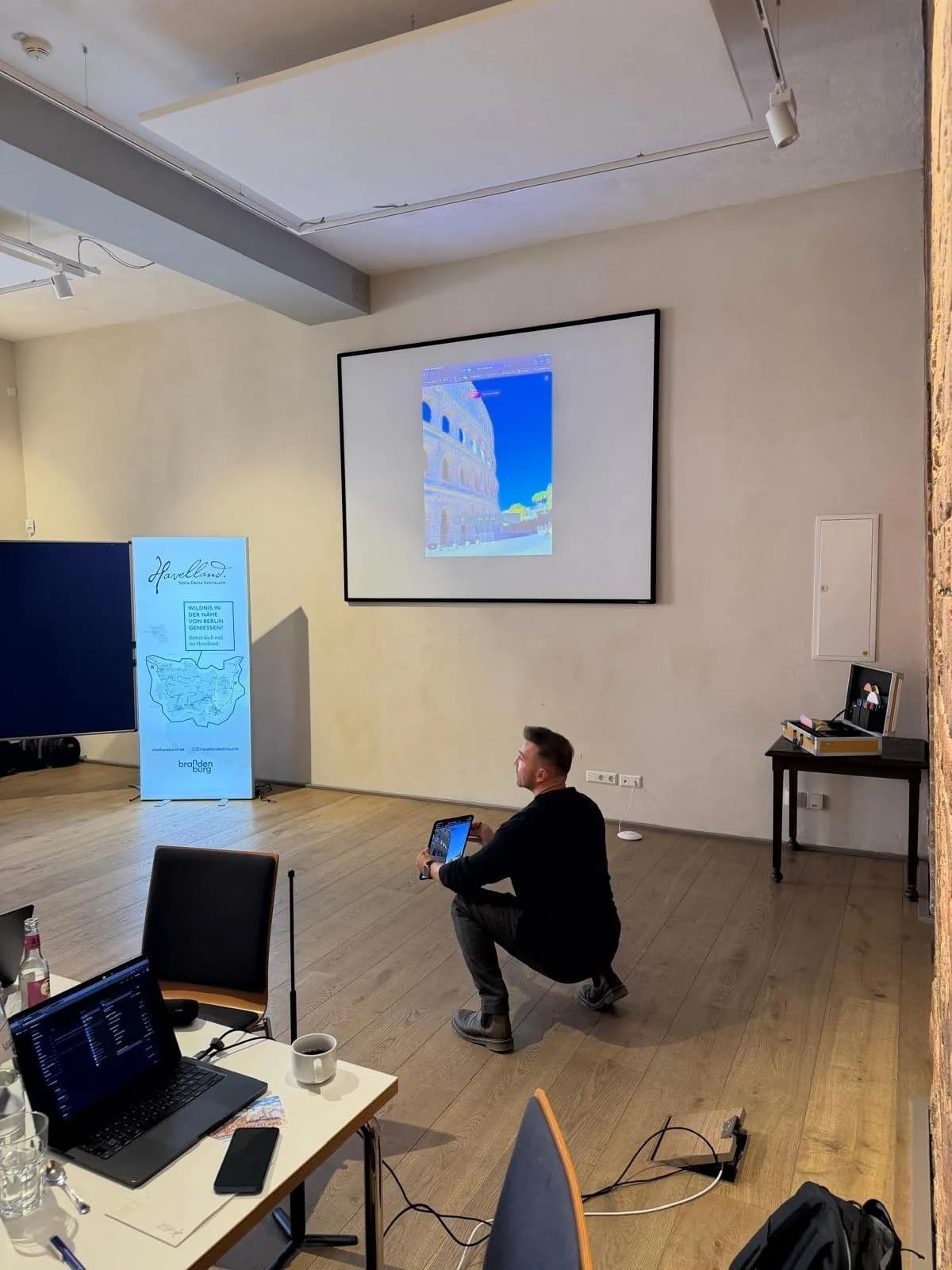 Viktor Waal zeigt ein AR-Portal auf dem Tablet, das Bild wird auf die Leinwand übertragen